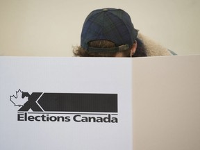 A woman marks her ballot behind a privacy barrier in the riding of Vaudreuil-Soulanges, west of Montreal, on October 19, 2015. A Federal Court judge is ordering the chief electoral officer to take a second look at whether voting day this October needs to be moved because it falls on a Jewish holiday.