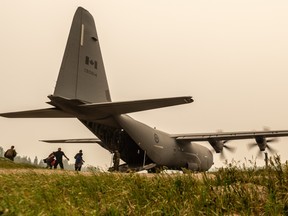 Canadian Armed Forces members help load evacuees on to a plane as smoke from a forest fire fills the sky near Pikangikum First Nation, Ont. in this undated handout photo. (THE CANADIAN PRESS/HO, Canadian Armed Forces)