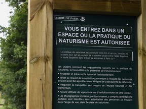 Graphic content / Two naked people walk past a sign reading "you are entering a space where the practice of naturism is authorized" at a newly opened space for naturists at the Bois de Vincennes park in Paris on August 31, 2017.