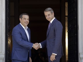 Greece's newly-elected prime minister Kyriakos Mitsotakis (R) shakes hands with outgoing prime minister Alexis Tsipras, as Tsipras leaves the Maximos Mansion on July 8, 2019 in Athens, Greece.