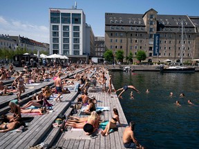 Locals and tourists enjoy the warm weather at Ofelia Square, in front of the National Theatre in Copenhagen, Denmark, on July 25, 2019. (LISELOTTE SABROE/AFP/Getty Images)