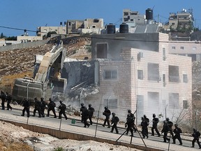 Israeli forces patrol as machinery demolishes a Palestinian building in the village of Sur Baher which sits on either side of the Israeli barrier in East Jerusalem and the Israeli-occupied West Bank July 22, 2019. (REUTERS/Mussa Qawasma)