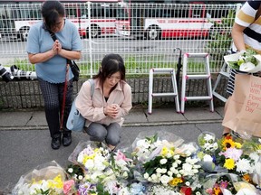 Women pray outside the Kyoto Animation building which was torched by arson attack, in Kyoto, Japan, July 19, 2019.