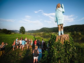 People gather around what conceptual artist Ales 'Maxi' Zupevc claims is the first ever monument of Melania Trump, set in the fields near the town of Sevnica, during a small inauguration celebration on July 5, 2019. (Jure Makovec /AFP)