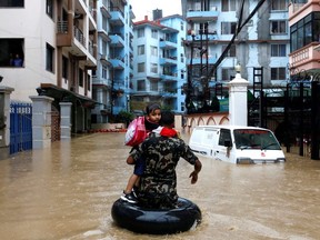 A member of Nepalese army carrying a child walks along the flooded colony in Kathmandu, Nepal on July 12, 2019.