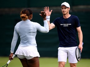 Andy Murray high fives mixed doubles partner Serena Williams during a Wimbledon practice session July 5, 2019 in London. (Laurence Griffiths/Getty Images)