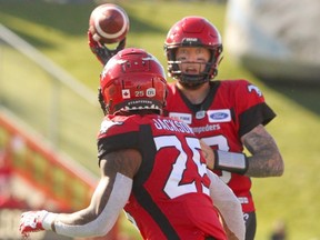 Stampeders quarterback Bo Levi Mitchell (rear) connects with running back Don Jackson during first half CFL action at McMahon Stadium in Calgary on June 29, 2019.