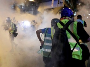 Protesters and journalists are seen after tear gas was fired by police outside the Legislative Council building, after demonstrators stormed the building on the anniversary of Hong Kong's handover to China in Hong Kong, China, on Monday, July 1, 2019.