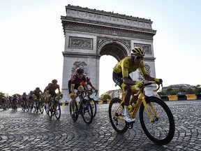 Colombia's Egan Bernal (R), wearing the overall leader's yellow jersey (C-R) and cyclists ride down the Champs Elysees avenue next to the Arc de Triomphe during the 21st and last stage of the 106th edition of the Tour de France cycling race between Rambouillet and Paris Champs-Elysees, in Paris, on July 28, 2019.