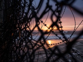 The sun sets behind the barbed wire of the U.S.-Mexico border in Playas de Tijuana, Baja California state, on June 29, 2019, Mexico.