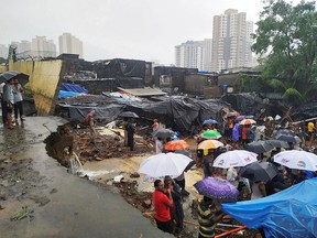 People stand among the debris after a wall collapsed on an encampment of huts due to heavy rain in Mumbai, India, July 2, 2019.