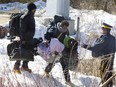 RCMP officers help a group of asylum seekers to cross a ditch as they crossed from the U.S. into Canada illegally at the border at Roxham Road in Hemmingford on Feb. 20, 2017.
