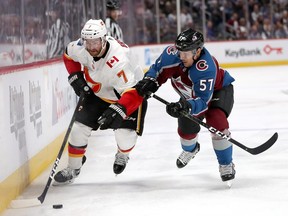 T.J. Brodie of the Calgary Flames fights on the boards with Gabriel Bourque of the Colorado Avalanche in the third period during Game 3 of the Western Conference First Round during the 2019 NHL Stanley Cup Playoffs at the Pepsi Center in Denver on April 15.