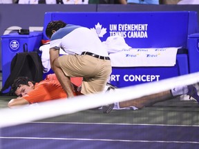 Milos Raonic receives medical attention for his back during his match against Montreal's Félix Auger-Aliassime at the Rogers Cup on Wednesday night.