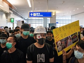 Protesters hold placards as they block the departure gate of the Hong Kong International Airport Terminal 2 during a demonstration on August 13, 2019 in Hong Kong, China.  (Photo by Anthony Kwan/Getty Images)