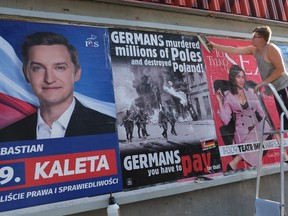 A worker puts up posters, including one that demands monetary reparations from Germany for the destruction Germany inflicted on Poland during World War II, on the eve of the 80th anniversary of the outbreak of World War II on August 31, 2019 in Warsaw, Poland. (Sean Gallup/Getty Images)