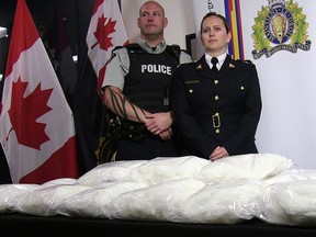 RCMP Cpl. Jon Cormier and RCMP Insp. Charlene O'Neill stand over seized methamphetamine from a truck at a Canada-U.S. border crossing in Alberta during a press conference in Calgary on Thursday, August 1, 2019.