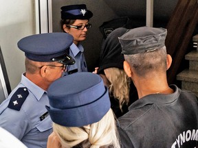Police officers surround a British teenager accused of falsely claiming she was gang raped by Israeli tourists, as she leaves the Famagusta District Court in Paralimni, Cyprus, on August 19, 2019. (IAKOVOS HATZISTAVROU/AFP/Getty Images)