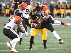 Receiver Branlon Addison of the Hamilton Tiger-Cats is tackled by B.C. Lions' linebacker Maleki Harris.