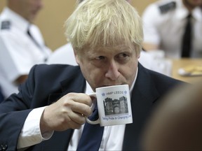 UK Prime Minister Boris Johnson takes a drink from a prison mug as he talks with prison staff during a visit to Leeds prison on August 13, 2019 in Leeds, England.
