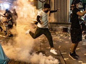 HONG KONG, CHINA - AUGUST 14: A protester attempts to kick a tear gas canister during a demonstration on Hungry Ghost Festival day in Sham Shui Po district on August 14, 2019 in Hong Kong, China. Pro-democracy protesters have continued rallies on the streets of Hong Kong against a controversial extradition bill since 9 June as the city plunged into crisis after waves of demonstrations and several violent clashes. Hong Kong's Chief Executive Carrie Lam apologized for introducing the bill and declared it "dead", however protesters have continued to draw large crowds with demands for Lam's resignation and completely withdraw the bill. (Photo by Anthony Kwan/Getty Images)
