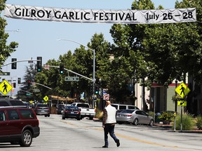 A man walks beneath a sign advertising the nearby Gilroy Garlic Festival after a mass shooting took place at the event yesterday on July 29, 2019 in Gilroy, Calif.