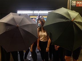 Protesters use umbrella to shield themselves during a protest to prevent commuters from reaching work in business districts at Lai King MTR station in Hong Kong on Aug. 5, 2019.