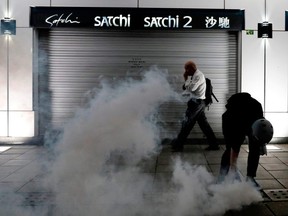 A man walks past an anti-extradition bill protester as he tries to pick up a tear gas canister at Tsim Sha Tsui after a demonstration in Hong Kong, China, on Saturday, Aug. 10, 2019.