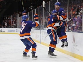 From left to right, Islanders players Jordan Eberle, Adam Pelech and Josh Bailey celebrate Bailey's game winning overtime goal against the Penguins in Game One of the NHL Eastern Conference First Round playoff series at NYCB Live's Nassau Coliseum on April 10, 2019 in Uniondale, N.Y.