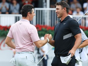 Brooks Koepka congratulates Rory McIlroy on the 18th green after McIlroy won the FedEx Cup and Tour Championship during the final round of the TOUR Championship at East Lake Golf Club on August 25, 2019 in Atlanta. (Streeter Lecka/Getty Images)