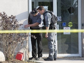 A member of the province's Special Investigation Unit (left) and London police officer examine the area where a man doused himself in gasoline and set himself on fire in front of the doors of the Citizenship and Immigration Canada office at 417 Exeter Roadin London, Ont. on Friday August 2, 2019. Derek Ruttan/The London Free Press/Postmedia Network