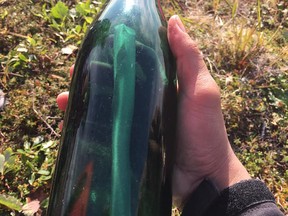 Tyler Ivanoff shows a bottle with a message inside he found washed up on the Alaskan shoreline. (Facebook photo)