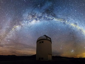 The warped shape of the stellar disk of the Milky Way galaxy, determined by mapping the distribution of young stars called Cepheids with distances set out in light years, is seen over the Warsaw University Telescope at Las Campanas Observatory in Chile, in an artist's rendition released Thursday, Aug. 1, 2019.
