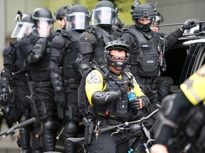 A cop removes his helmet to take a sip of water as alt-right groups march down the street during the End Domestic Terrorism rally on August 17, 2019 in Portland, Oregon. (Karen Ducey/Getty Images)