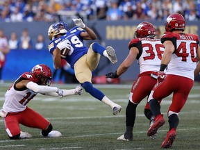 Winnipeg Blue Bombers receiver Kenny Lawler (centre) is spun around by Calgary Stampeders defensive back Royce Metchie (left) during CFL action in Winnipeg on Thurs., Aug. 8, 2019. Kevin King/Winnipeg Sun/Postmedia Network