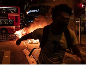 A pro-democracy protester runs away from a burning barricade outside of the Mongkok Police Station as a bus drives in front of it on September 22, 2019 in Hong Kong, China. Pro-democracy protesters have continued demonstrations across Hong Kong, calling for the city's Chief Executive Carrie Lam to immediately meet the rest of their demands; including an independent inquiry into police brutality, the retraction of the word riot to describe the rallies, and genuine universal suffrage as the territory faces a leadership crisis.