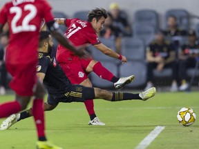 Toronto FC midfielder Tsubasa Endoh scores against Los Angeles FC while defended by Steven Beitashour on Saturday night in Los Angeles.