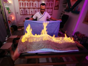 Massage therapist Abdel Rehim Saeid performs the "fiery towel" method to ease a patient's muscle pain in Gharbia, Egypt, Sept. 4, 2019. REUTERS/Mohamed Abd El Ghany