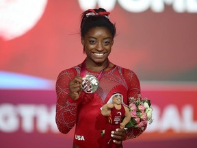 In this file photo taken on November 3, 2018, Gold medalist Simone Biles (C) from the US poses for a photograph with her medal during the 2018 FIG Artistic Gymnastics Championships at the Aspire Dome in Doha. - The brother of champion US gymnast Simone Biles has been arrested and charged in connection with a New Year's Eve shooting that left three people dead. Tevin Biles-Thomas, 24, was charged on August 29, 2019, with murder, voluntary manslaughter, felonious assault and perjury, according to a statement from police in Cleveland, Ohio, where the shooting happened.