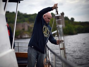 In this file photo taken on June 11, 2018 Professor Neil Gemmell takes samples on his boat as he conducts research into the DNA present in the waters of Loch Ness in the Scottish Highlands, Scotland on June 11, 2018.