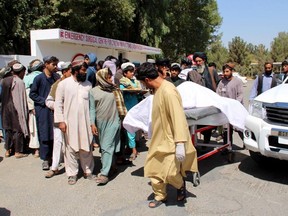 Afghan villagers carry a dead body on a stretcher outside a hospital following an airstrike in Lashkar Gah, the capital of Helmand province on September 23, 2019. - Afghanistan is investigating reports that 40 civilians, including children, were killed in an airstrike during a wedding celebration in southern Helmand province, officials said on September 23. The defence ministry said it would "share the result of the investigation" into the deaths overnight in Musa Qala district, which come less than a week after a drone killed at least nine civilians in Nangarhar province east of Kabul.