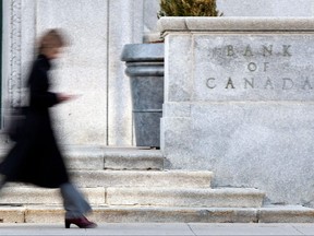 In this file photo taken on April 12, 2011, a woman walks past the Bank of Canada building in Ottawa.