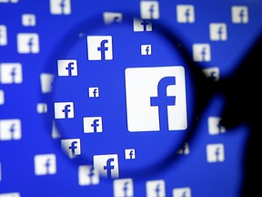 A man poses with a magnifier in front of a Facebook logo on display in this illustration taken in Sarajevo, Bosnia and Herzegovina, Dec. 16, 2015.