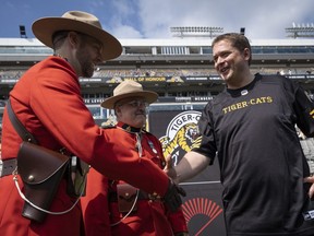Conservative Leader Andrew Scheer says hello to two Royal Canadian Mounted Police officers prior to CFL football action in Hamilton, Ont., on Monday, September 2, 2019. THE CANADIAN PRESS/Peter Power