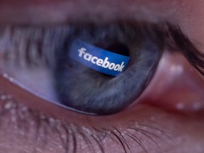 An illustration picture shows a person posing during a photo session showing the social platform Facebook logo reflected in the pupil of an eye on April 25, 2018, in Paris.