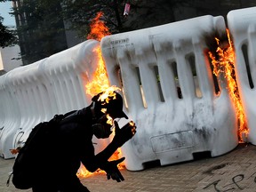 An anti-government protester catches fire after throwing Molotov cocktail during a demonstration near Central Government Complex in Hong Kong, Sept. 15, 2019.