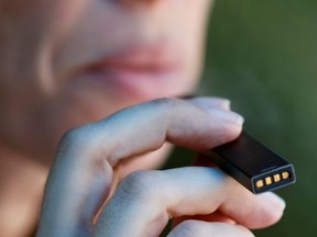 A woman smokes a Juul e-cigarette in this posed picture, near Jerusalem September 16, 2018.