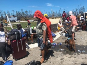 Survivors of Hurricane Dorian cover their heads to get some relief from the sun as they wait for relief flights off the heavily damaged island, at the nearly-destroyed Treasure Cay Airport in Abaco, Bahamas, on September 5, 2019. (REUTERS/Nick Brown)