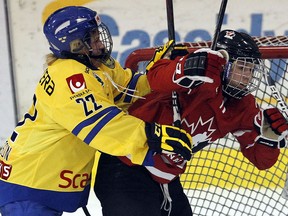 Sweden’s Meaghan Mikkelson bumps Canada’s Haley Irwin in the crease in Pembroke, ON Saturday, Mar. 30, 2013. (Darren Brown/Ottawa Sun)