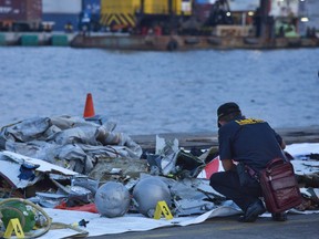 A forensic investigator looks through the remains of Lion Air flight JT 610 at the Tanjung Priok port on October 29, 2018 in Jakarta, Indonesia. Lion Air Flight JT 610 crashed shortly after take-off with no sign so far of survivors among the 189 people on board the plane.  (Photo by Ed Wray/Getty Images)